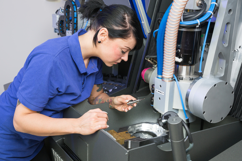 Technician in a dental lab working at a drilling or milling machine